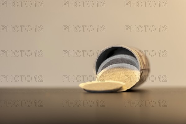 Coffee pods slide out of an open tin onto the table