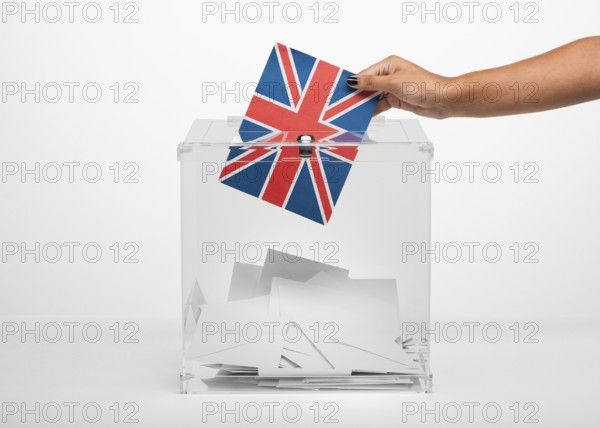 Person putting united kingdom flag card into ballot box