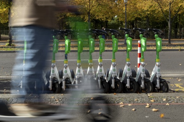 Traffic, mobility, motion blur, scooter riders and lined-up e-scooters from the provider Lime in