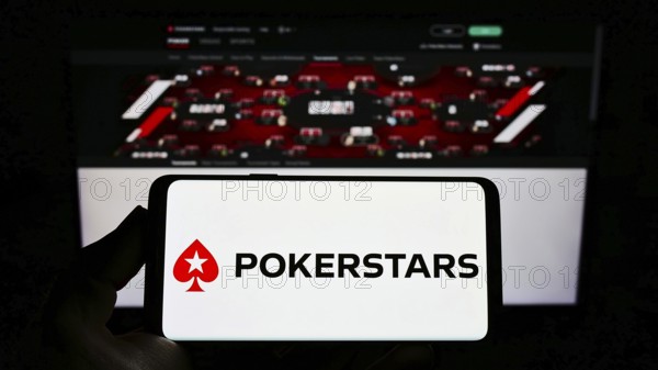 Stuttgart, Germany, 01-06-2022: Person holding smartphone with logo of online poker cardroom