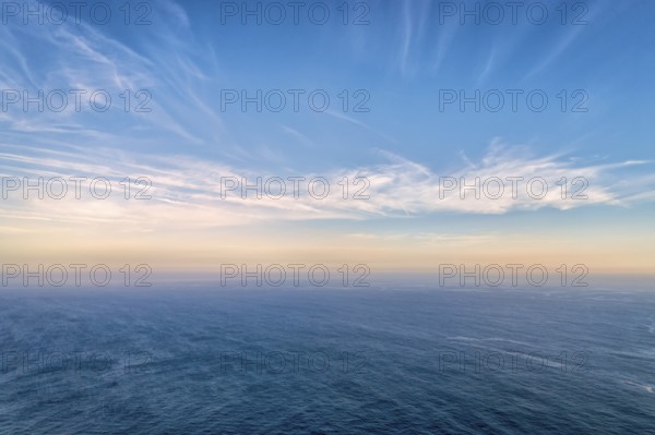 Beautiful seascape with calm sea or ocean waves. Atmospheric haze, colorful low clouds lit by