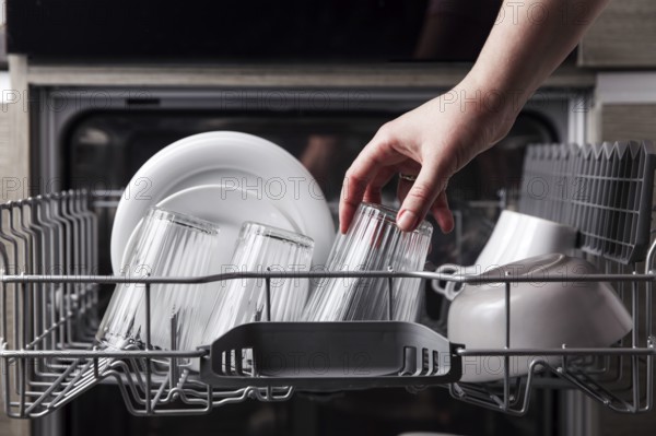 Close-up of female hand loading dished to, empty out or unloading from open automatic stainless