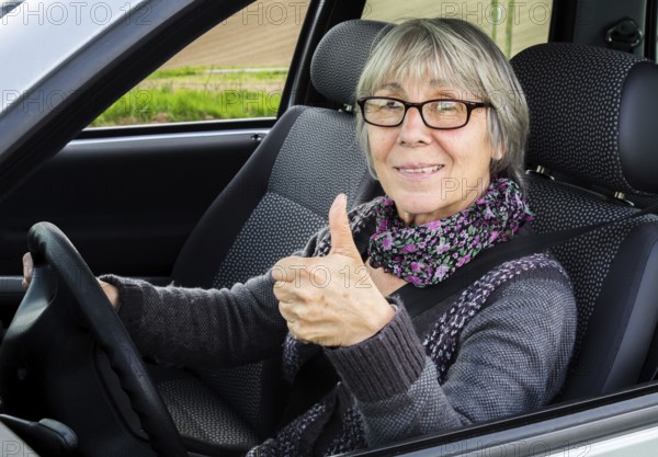 Senior citizen in car gives thumbs up