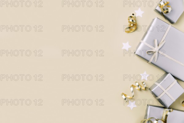 Light beige or yellow flat lay background with gift boxes in glossy silver craft paper packaging
