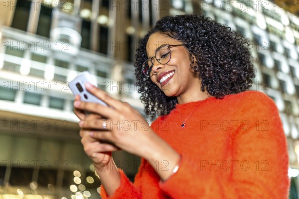 Smiling businesswoman engaging with a mobile phone app while enjoying the vibrant city center at
