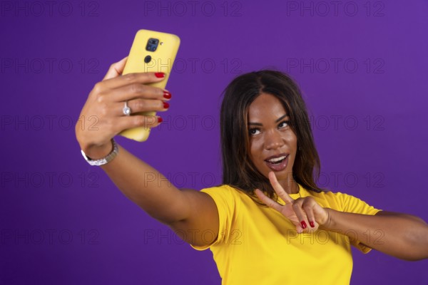 Studio portrait with purple background of an african urban woman gesturing success while taking a
