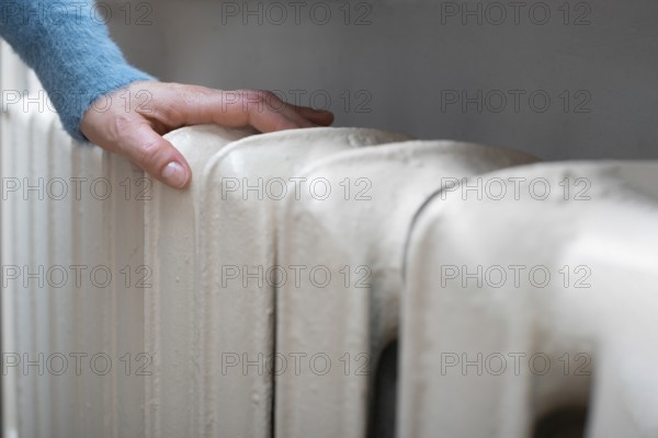 Caucasian female warming up hands near Hot Water Radiator. Space for text