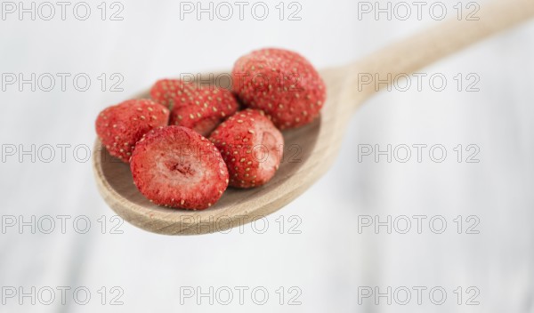 Strawberries (dried) as high detailed close-up shot on a vintage wooden table, selective focus