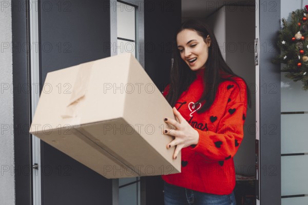 Cheerful young woman excited over a package she just received. Woman getting her christmas gift in
