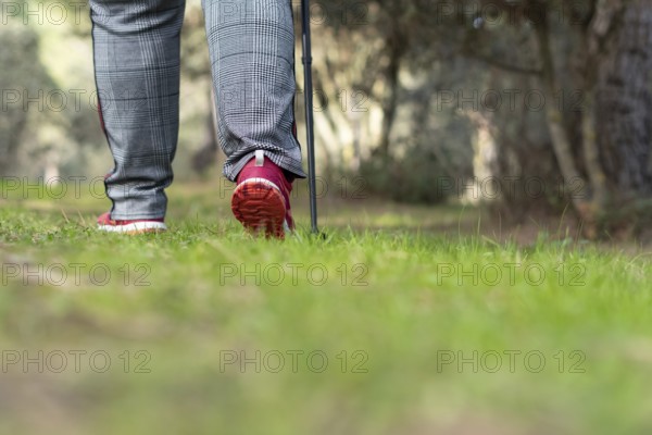 Rear view of a woman walking in the field with trekking pole