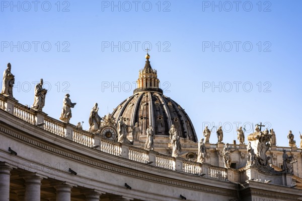 Architectural detail with the dome of St Peter's Basilica and statues under a clear sky, Rome