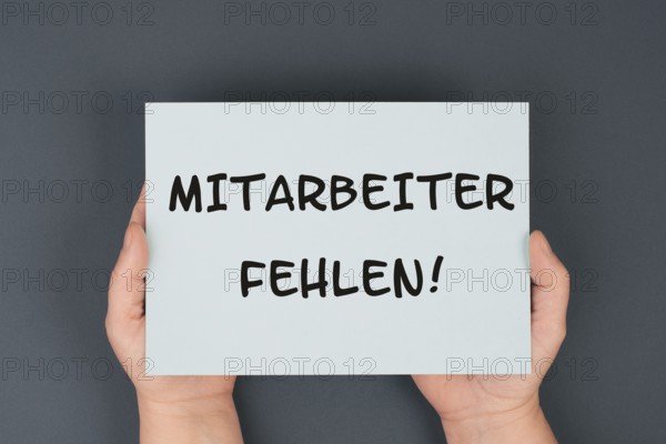 The words shortage of employees are standing in german language on the paper, skilled workers are
