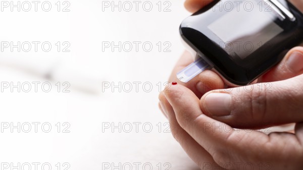 Pierced caucasian finger ready to measure glucose level by glucose meter closeup view with