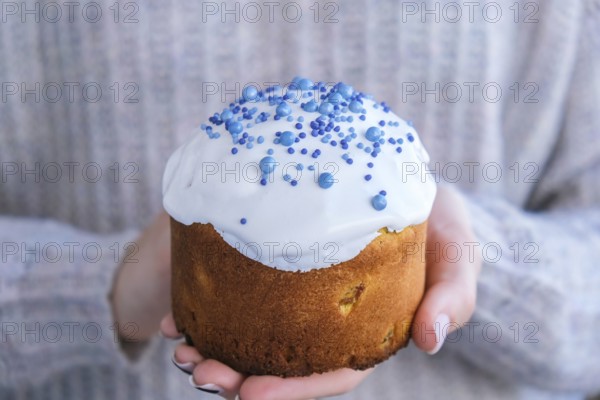 The cook Hands hold Easter cake with white topping and blue sprinkles. Woman holding traditional