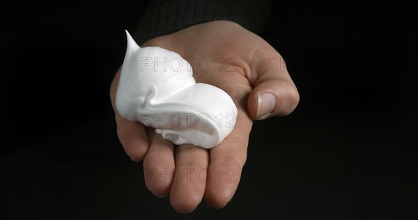 Hand of Woman and shaving foam against Black Background