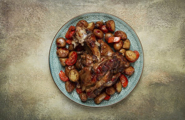 Pork knuckle baked with vegetables, new potatoes, on a plate, homemade, no people