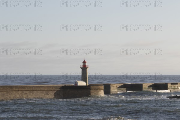 Lighthouse Farolim de Felgueiras in the Atlantic Ocean in the evening light at the beach promenade