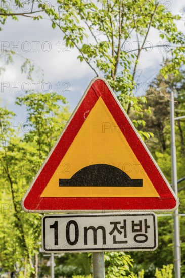 A traffic sign warning of a speed bump ahead with Korean text beneath, in Daejeon, South Korea,