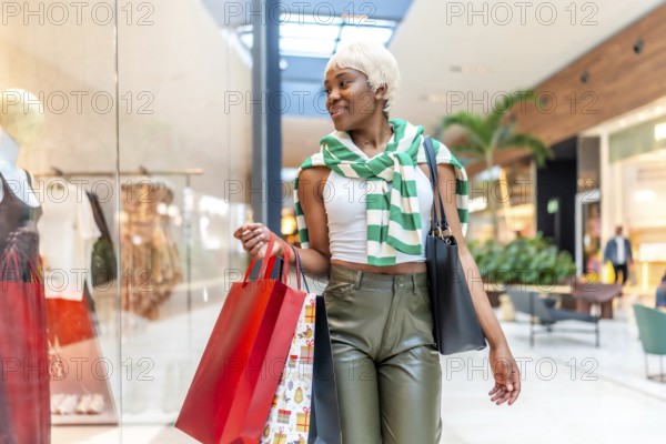 African woman strolling and looking at a shop window in a shopping mall