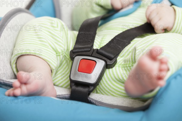 Little baby child fastened with security belt in safety car seat