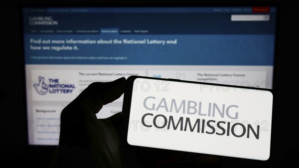 Stuttgart, Germany, 04-01-2023: Person holding cellphone with logo of British public body Gambling