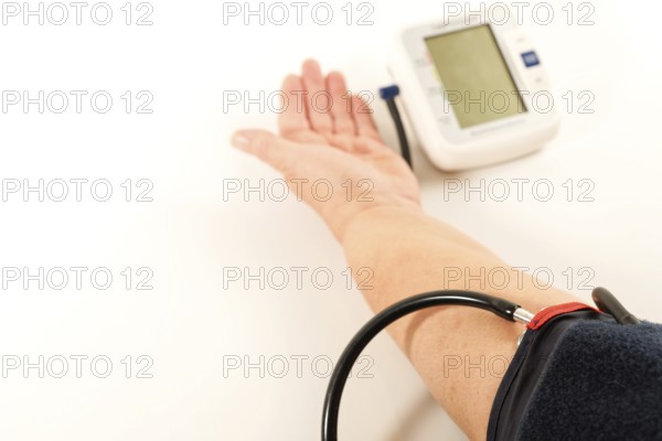 Woman's arm taking blood pressure on a white table with space for text