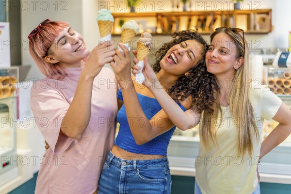 Funny diverse female friends toasting with ice cream cones in store