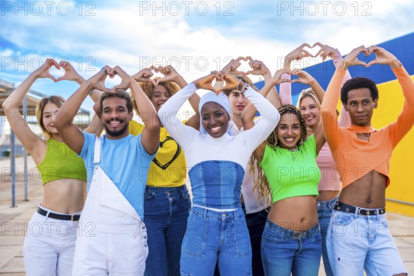 Multi-ethnic young people standing gesturing heart shape with hands outdoors in a urban space
