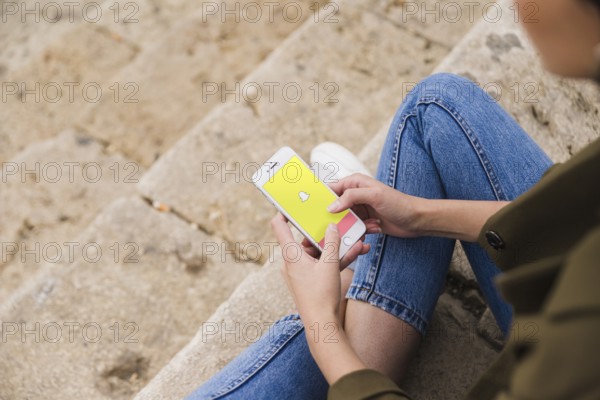 Woman sitting staircase using snapchat app smartphone