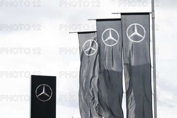 The Daimler Mercedes Benz logo on flags fluttering in the wind