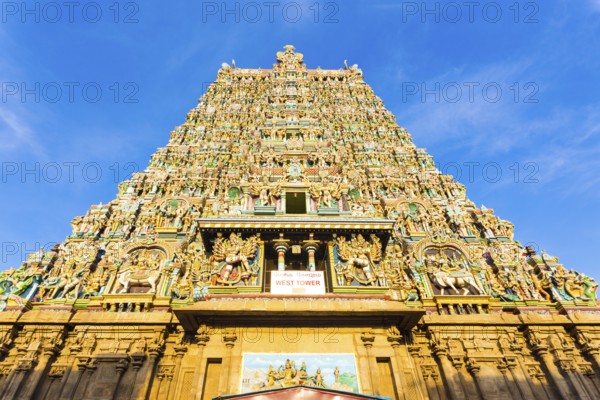 Centered west tower gateway of Meenakshi Amman Temple covered in colorful statues of gods on a blue
