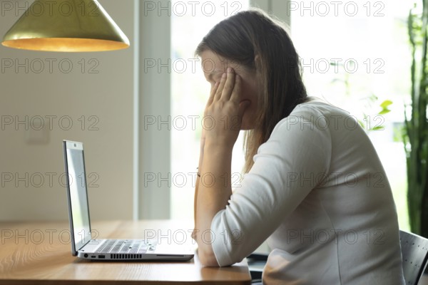 Young woman suffers from burnout in home office on laptop, Freiburg, Baden-Württemberg, Germany,