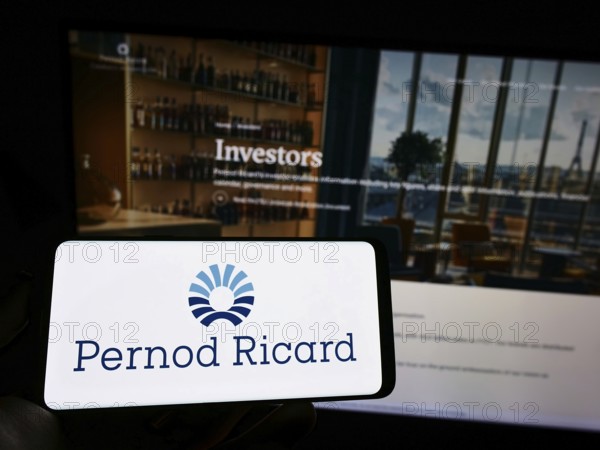 Stuttgart, Germany, 10-14-2022: Person holding mobile phone with logo of French beverage company
