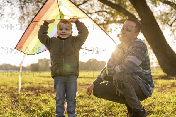Father son playing together with colourful kite