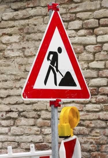 Traffic sign at a construction site with a brickwall in the background
