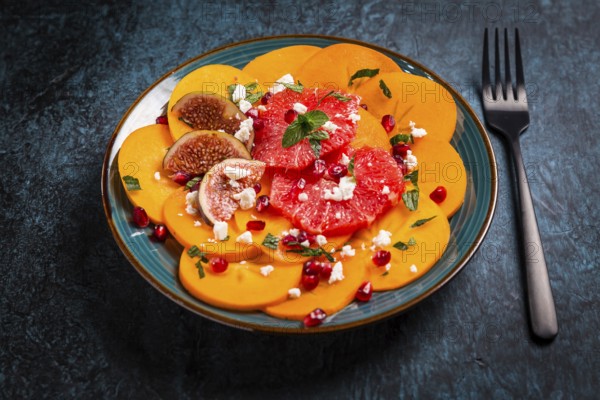 Healthy winter salad - Persimmon carpaccio salad with pomegranate, feta cheese, pink grapefruit and