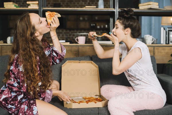 Two hungry young women eating pizza