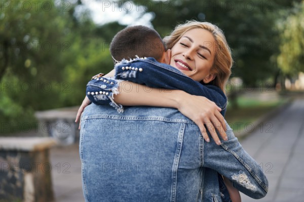 Happy meeting of two lovers hugging in the street. Young woman greeting her boyfriend embracing