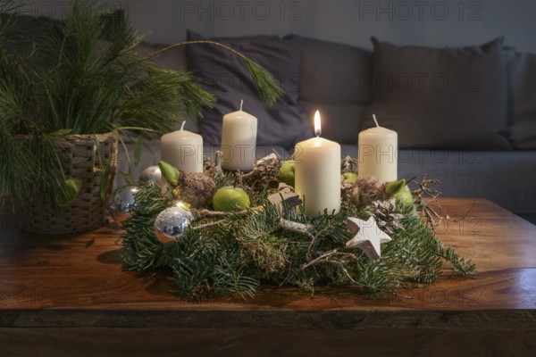 First Advent, wreath with one burning white candle and Christmas decoration on a wooden table in