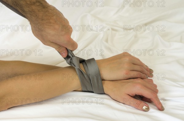 Great concept of female sexual submission. Man tying woman's hands with tie
