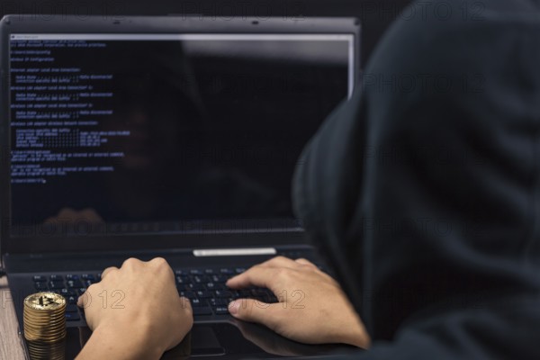Dangerous hooded hacker on laptop breaks computer security sistem and steal bitcoin cryptocurrency