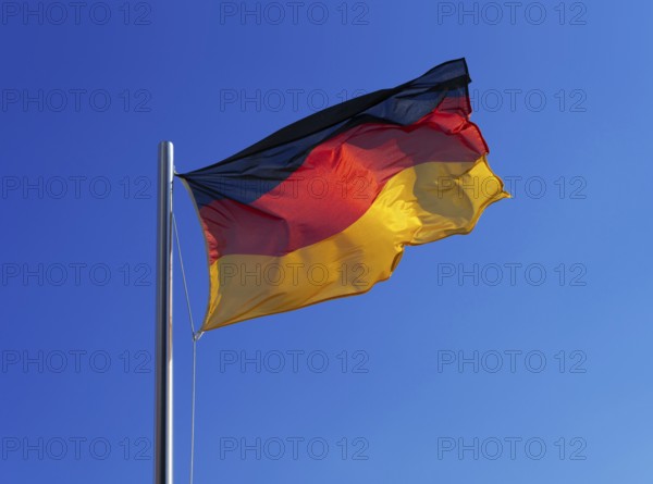 German flag, national flag in strong wind against blue sky
