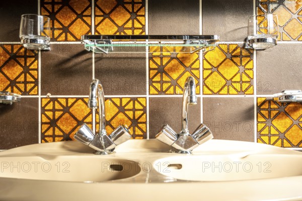 Retro and vintage bathroom sink, with mid century tiles, orange and brown colored