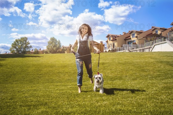 Adult Caucasian happy woman run in the park with her beloved dog Schnauzer. fun mood