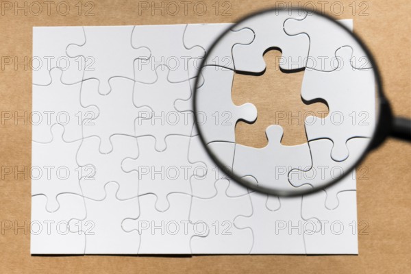 Magnifying glass missing puzzle brown paper textured backdrop