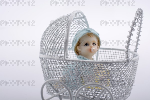 Little baby doll in baby carriage on a white background