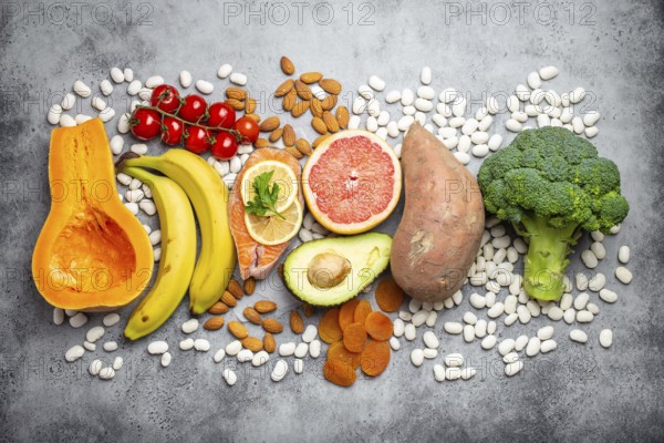 Vegetables, fruit and foods containing potassium over gray stone background, top view. Natural