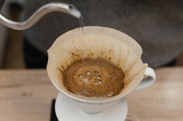 High angle male barista pouring hot water coffee filter