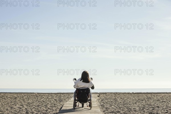 Back view woman wheelchair beach. Resolution and high quality beautiful photo