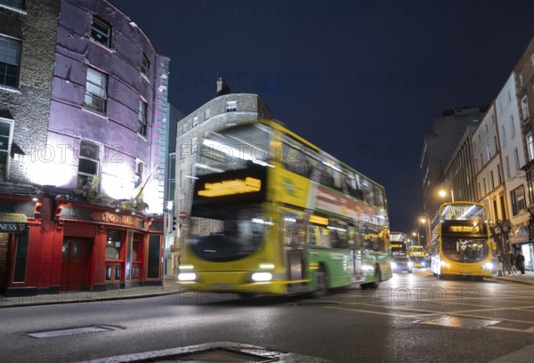 A Dublin bus speeds past Doyle's pub and on towards Trinity College at night time. Dublin, Ireland,